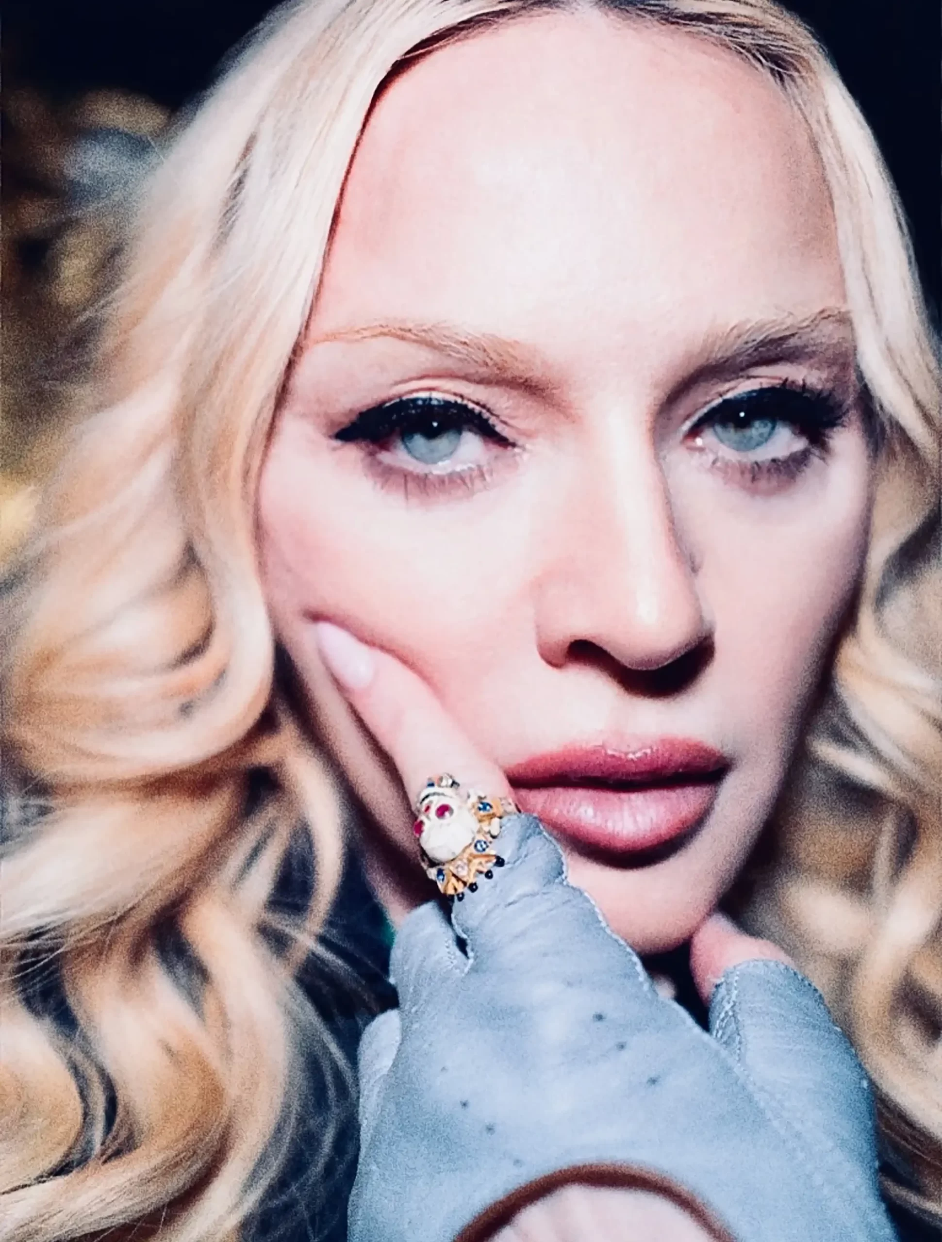 Madonna într-un portret de prim-plan, cu o mână înmănușată atingându-i obrazul.